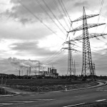 Power pole with power station in background black and white
